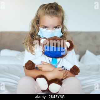 Covid, ragazza e orsacchiotto sopportano l'amore e la cura per la sicurezza e la consapevolezza nella quarantena pandemica nel paese. Ritratto di un bambino piccolo che gioca medico tenendo carino Foto Stock