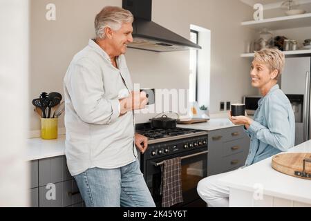 Coppia senior, caffè e parlare in cucina con tazza, bevande o drink a casa. Pensione, sorriso e anziani felice uomo e donna bere tè Foto Stock