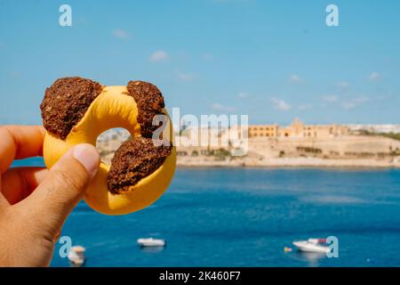 Primo piano di un uomo che detiene un gasel maltese qaghaq tal-ghasel, conosciuto anche come anello di miele in inglese, a la Valletta, Malta Foto Stock