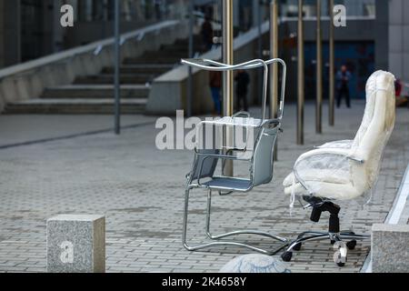 sedie da ufficio in piedi sul marciapiede Foto Stock