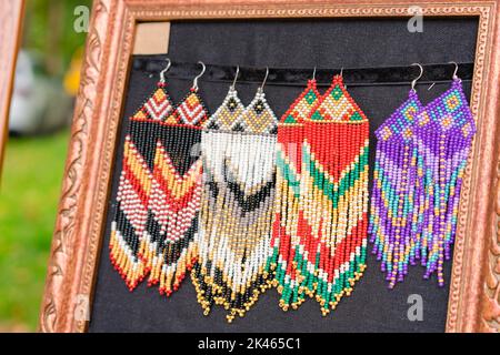 Colorati orecchini a perline in stile boho - gioielli in stile folk fatti a mano presso la bancarella dei souvenir, il mercato delle pulci o il mercato di strada. Messa a fuoco selettiva Foto Stock