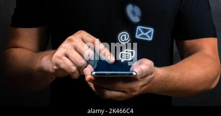 Contattaci, mano di uomo d'affari che tiene cellulare con posta, telefono, e-mail icona. Cutomer concetto di supporto. Avvicinati alle mani maschili utilizzando il wit dello smartphone Foto Stock