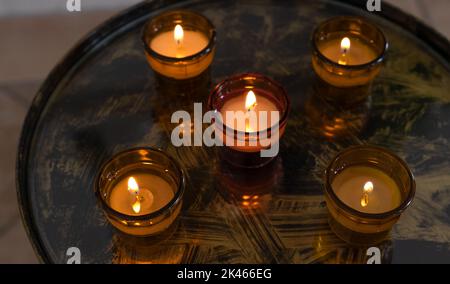 Cinque candele votive bruciate in ciotole di vetro su un vassoio Foto Stock
