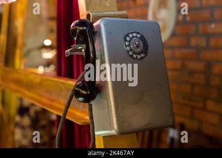 Vecchio telefono sovietico con una tabella di avvertimento circa il supplemento per una chiamata lunga e con i numeri di telefono di emergenza (scritti in russo) appesi nello stand Foto Stock