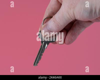 uomo in possesso di una chiave edificio isolato su uno sfondo rosa Foto Stock