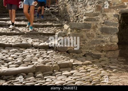 Gambe e piedi che camminano lungo ciottoli e gradini su stradine acciottolate a Clovelly, North Devon, Regno Unito, Foto Stock