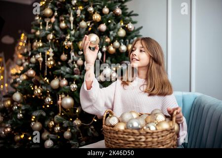 Ragazza adolescente carina in una stanza con un albero di Natale decorato. Le vacanze invernali. Foto di alta qualità Foto Stock