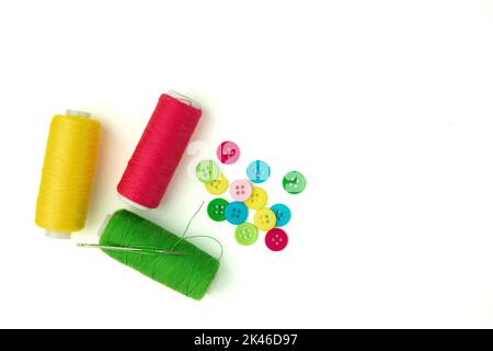 composizione con fili e bottoni su sfondo bianco, cucito a tema con bottoni colorati e filo Foto Stock