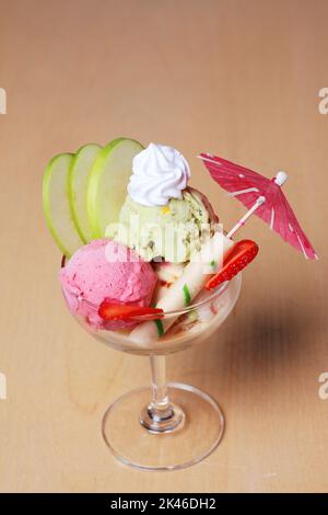 Gelato alla fragola e al tè verde con frutta fresca decorata in stile classico su un tavolo di legno per dessert Foto Stock