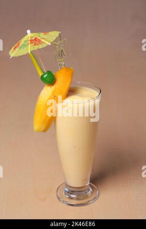 Bicchiere di frullato di mango o di milkshake con frutta fresca decorata in stile classico su tavolo di legno per dessert Foto Stock