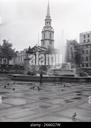 1958, storico, un uomo vicino ad una fontana in una deserta Trafalgar Square, Westminster, Londra, Inghilterra, Regno Unito. La chiesa parrocchiale di San Martino-in-the-Fields, con guglia, è visibile sullo sfondo. Foto Stock