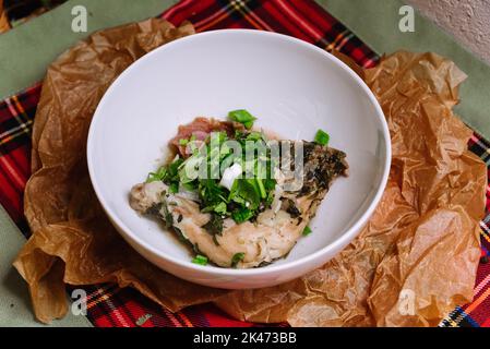 Piatto di pollame. Pollo Chahbili in salsa di spezie aromatiche, cipolle, prezzemolo fresco e coriandolo verde, aglio. In una ciotola bianca profonda. Foto Stock