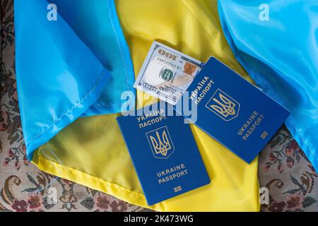 Passaporto ucraino su bandiera blu-gialla. Dollari sulla bandiera Ucraina Foto Stock