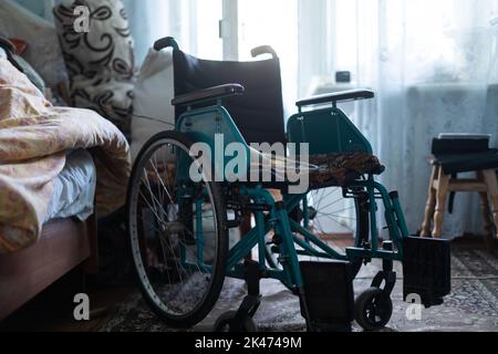 sedia a rotelle vuota in una vecchia casa molto povera Foto Stock