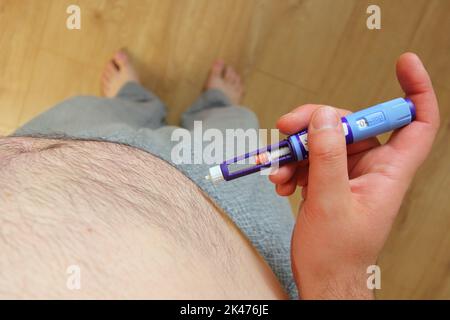 Uomo in sovrappeso che applica iniezione di medicinale per il diabete (siringa) nello stomaco, nella pancia Foto Stock