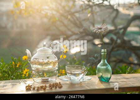 Tè al crisantemo con vapore caldo e marmellata di patate dolci sul tavolo di legno, sullo sfondo del cortile nel pomeriggio luce solare Foto Stock