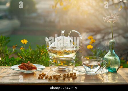 Tè al crisantemo con vapore caldo e marmellata di patate dolci sul tavolo di legno, sullo sfondo del cortile nel pomeriggio luce solare Foto Stock