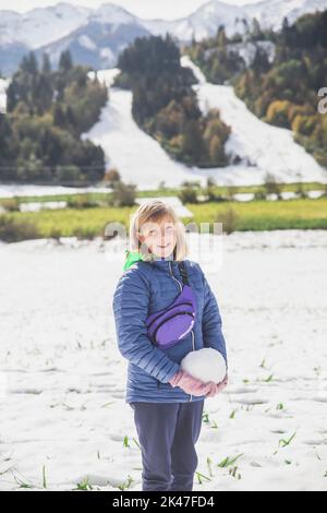 La ragazza bionda fa un pupazzo di neve in Slovenia nelle Alpi Foto Stock