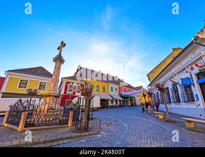 La piazza principale (Fo Ter) con vecchie case colorate e la croce di peste in pietra scolpita, Szentendre, Ungheria Foto Stock