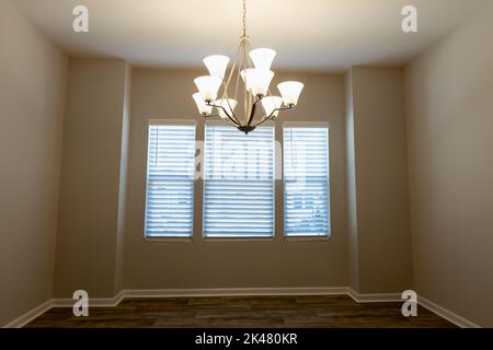 Sala da pranzo vuota in un appartamento con lampadario a soffitto e finestra. Foto Stock