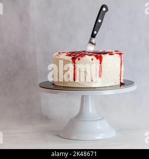 Torta di mostro sanguinante con coltello sul piedistallo per torte Foto Stock