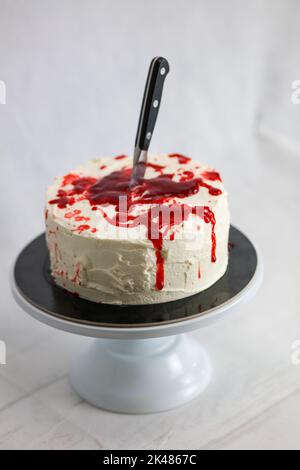 Torta di mostro sanguinante con coltello sul piedistallo per torte Foto Stock