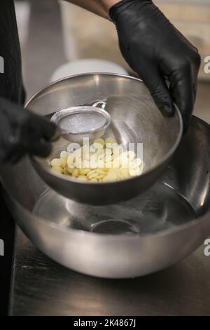 chef che prepara per glassa una torta all'acqua lilla nel laboratorio professionale della cucina Foto Stock