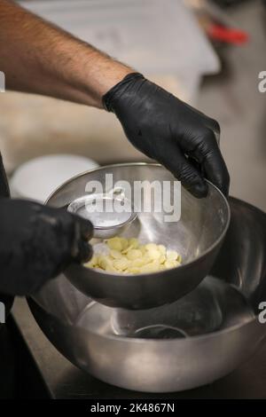 chef che prepara per glassa una torta all'acqua lilla nel laboratorio professionale della cucina Foto Stock