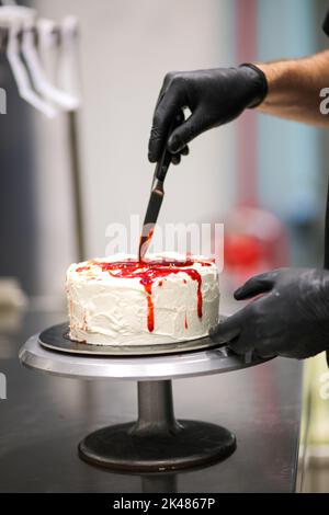 Torta di mostro sanguinante con coltello sul piedistallo per torte Foto Stock