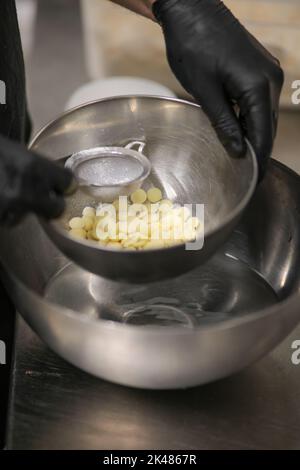 chef che prepara per glassa una torta all'acqua lilla nel laboratorio professionale della cucina Foto Stock