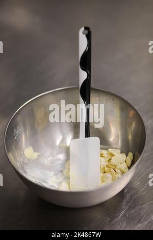 chef che prepara per glassa una torta all'acqua lilla nel laboratorio professionale della cucina Foto Stock