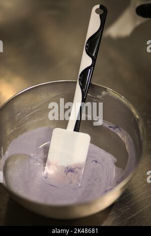 chef che prepara per glassa una torta all'acqua lilla nel laboratorio professionale della cucina Foto Stock