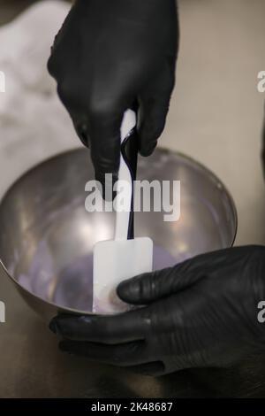 chef che prepara per glassa una torta all'acqua lilla nel laboratorio professionale della cucina Foto Stock