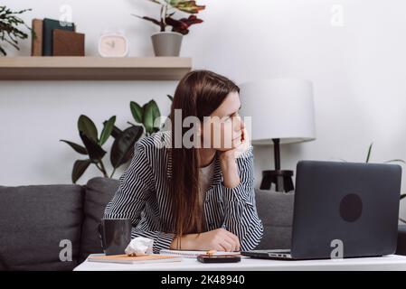 Giovane donna pensierosa seduta sul divano con notebook pensando di ispirazione sognando guardando lontano profondamente perso nei pensieri, ragazza penosa computer scrittura Foto Stock