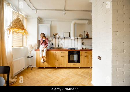Cucina moderna interna con persona seduta sul tavolo Foto Stock