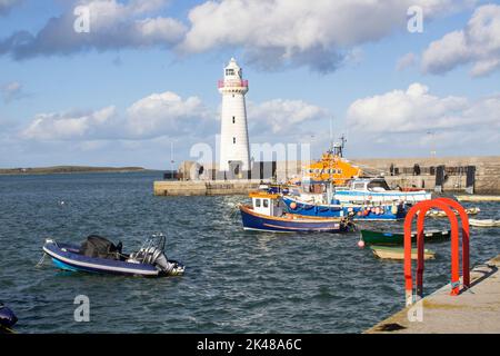 30 settembre 2022 le barche ormeggiate nel porto di Donaghadee, Irlanda del Nord, sotto la luce solare soffusa dei primi mesi dell'autunno, sotto l'ombra del faro locale. Foto Stock