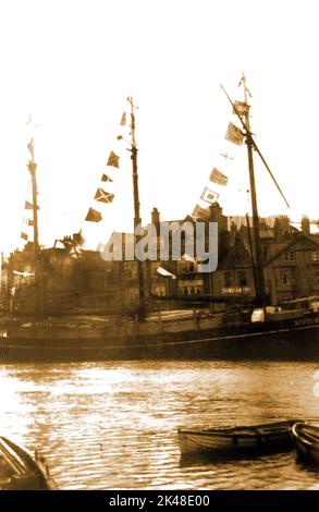 Una fotografia molto precoce di una nave a tre alberi ormeggiata appena sopra il ponte di Whitby, North Yorkshire, Regno Unito, abbellita da bandiere. Dietro di essa si può vedere un cartello a muro per il Rol Whisky (o whisky) sulle volte del vino di Falkingbridge (ora demolito) Foto Stock