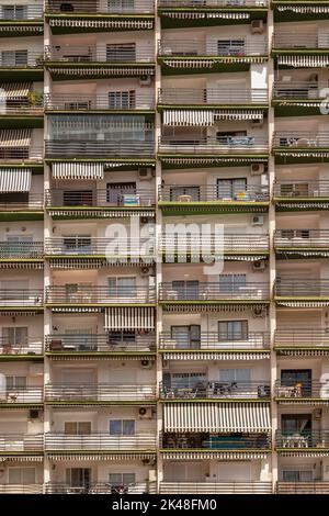 Balconi di un alto edificio di appartamenti con facciate, finestre e tende nel centro di Marbella, in Spagna. Foto Stock