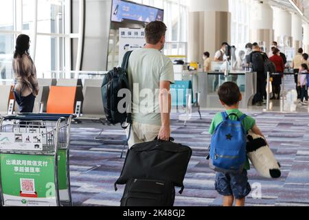 vista sul retro dei viaggiatori padre e figlio con bagaglio e borsa e maschera facciale per il check-in e la partenza in aeroporto Foto Stock