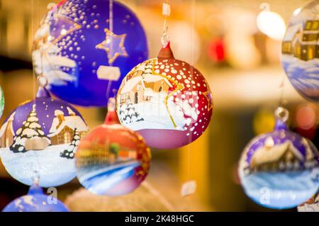 Bancarelle del Bazaar dell'Avvento con vetro, legno, souvenir di natale in ceramica in un negozio. Primo piano delle decorazioni festive per l'albero nel mercato notturno di strada d'inverno Foto Stock