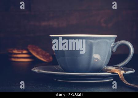 Primo piano di tazza blu e piattino con biscotti al cioccolato senza glutine Foto Stock