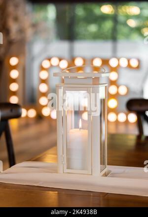 Bella cera vera candela che brucia in romantica location matrimonio con lettere d'amore illuminato fuori fuoco dietro. Foto Stock