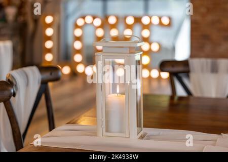 Bella cera vera candela che brucia in romantica location matrimonio con lettere d'amore illuminato fuori fuoco dietro. Foto Stock
