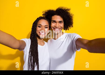 Il ritratto di due allegri partner rende selfie registrazione video isolato su sfondo giallo Foto Stock