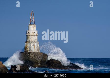 Faro colpito da onde che si tuffano su di esso durante l'ora blu Foto Stock