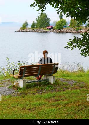 Donna su una panca in legno Foto Stock