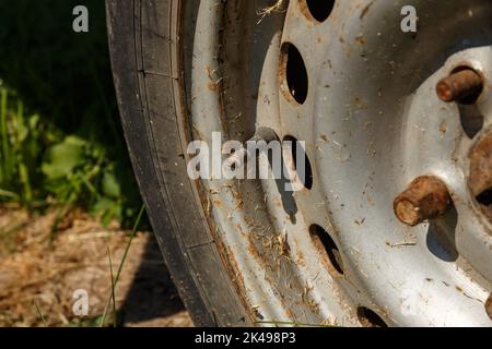 valvola schrader tappata e stelo su un pneumatico del veicolo con cerchio. vecchia ruota arrugginita alla luce del sole. Primo piano Foto Stock