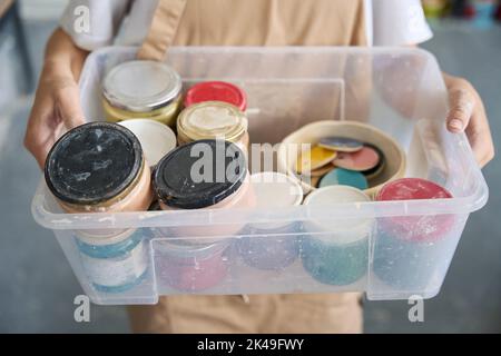 Donna tiene una scatola trasparente di vernici nelle sue mani Foto Stock