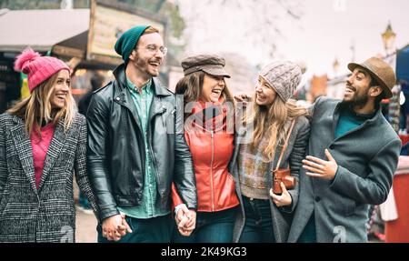 Gruppo di amici millenari a piedi nel centro di Londra - concetto di amicizia di nuova generazione su giovani multiculturali che indossano abiti invernali Foto Stock