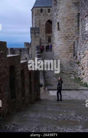 Giovane donna che cammina per la strada della storica città medievale fortificata di Carcassonne, Aude, Occitanie, Sud della Francia. Patrimonio mondiale dell'UNESCO si Foto Stock